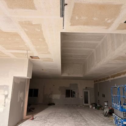 The gym space mid-buildout, with drywall hung, taped, and the ceiling framed out